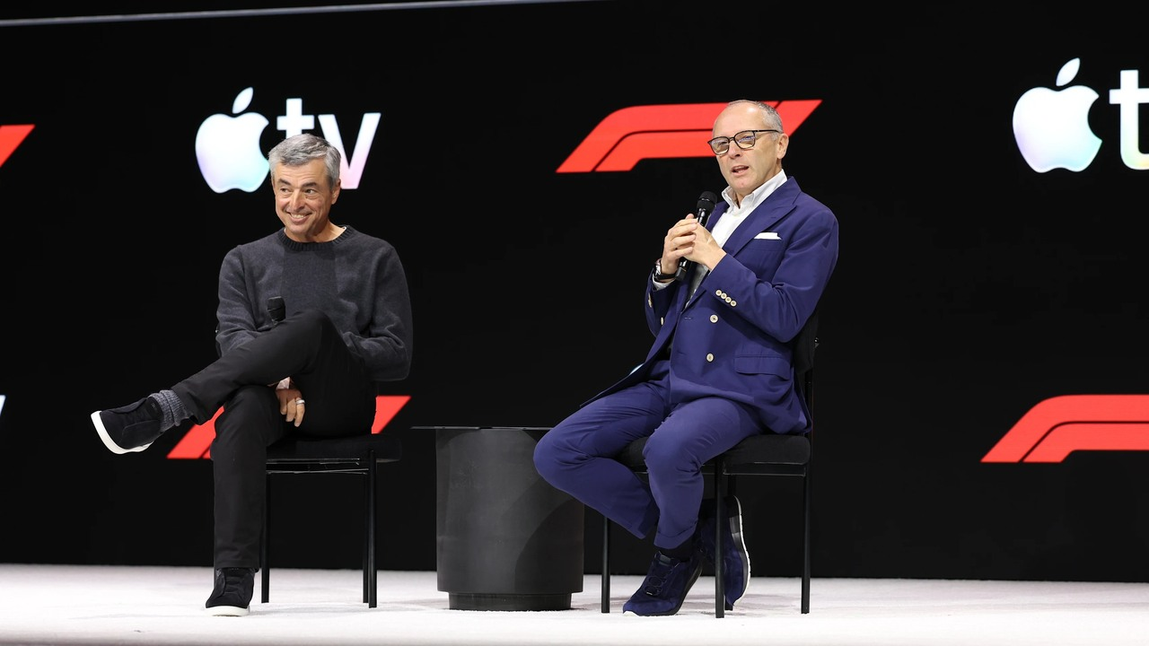 Stefano Domenicali and Eddy Cue sit on a Formula 1 stage