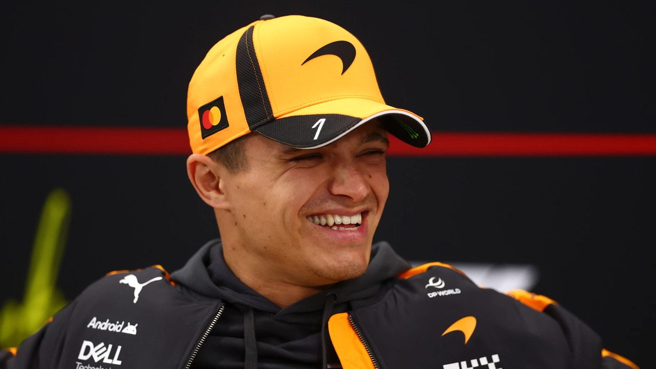 Lando Norris sorride con un cappellino e una maglia della McLaren.
