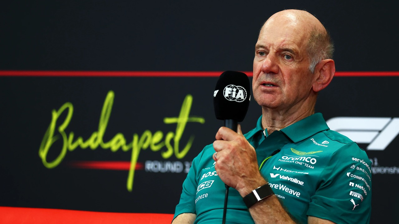 Adrian Newey speaks into a microphone while wearing Aston Martin team clothing