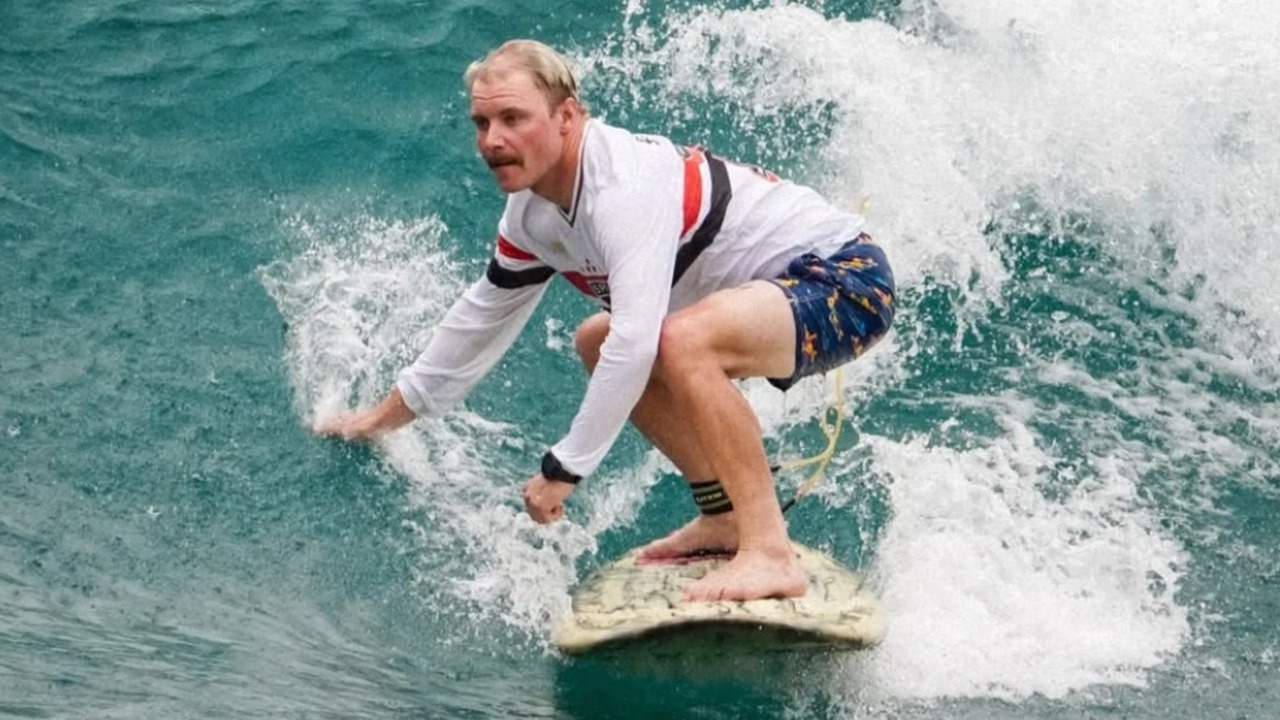 Valtteri Bottas rides a wave on a surfboard