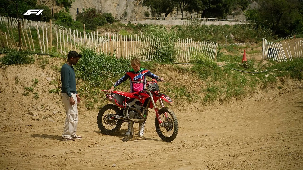 Liam Lawson stands beside a motorcycle on a dirt track