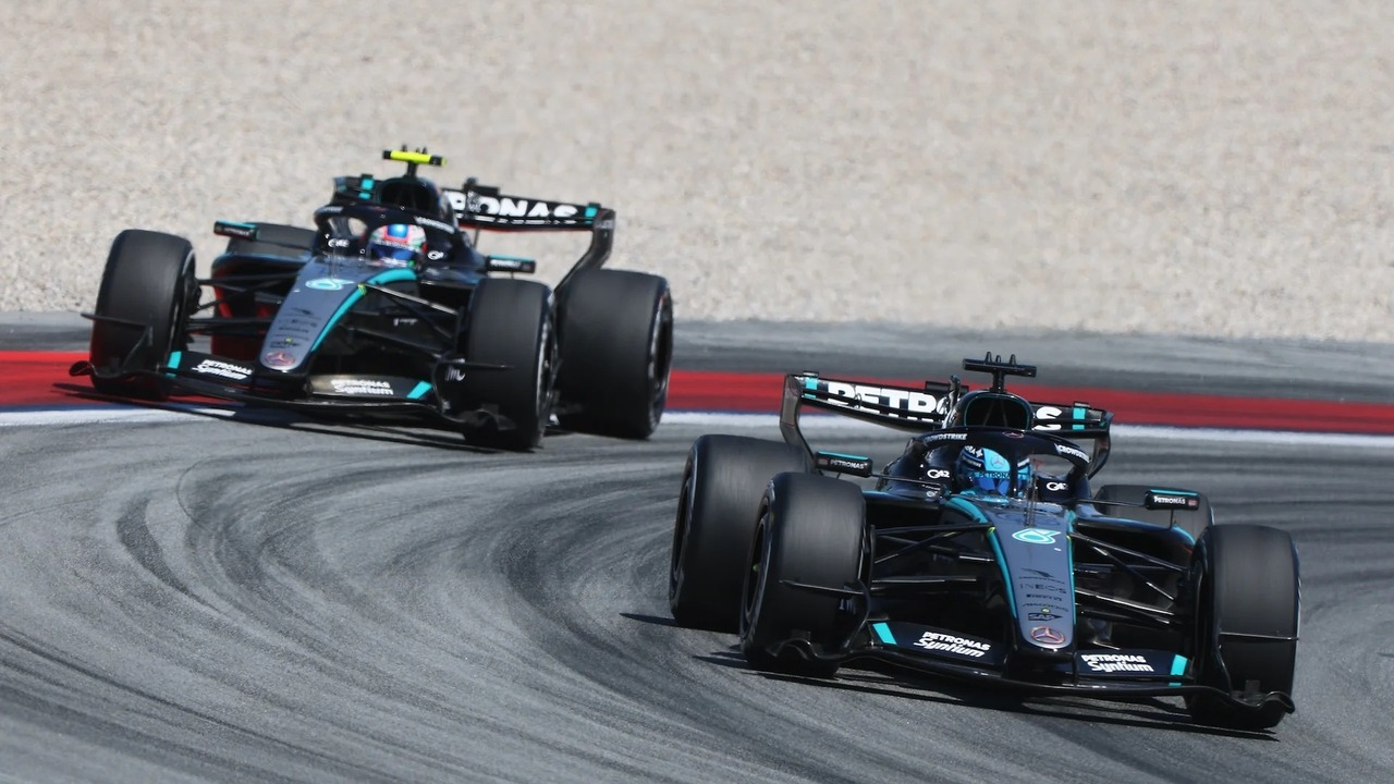 Two Mercedes Formula 1 cars race through a corner
